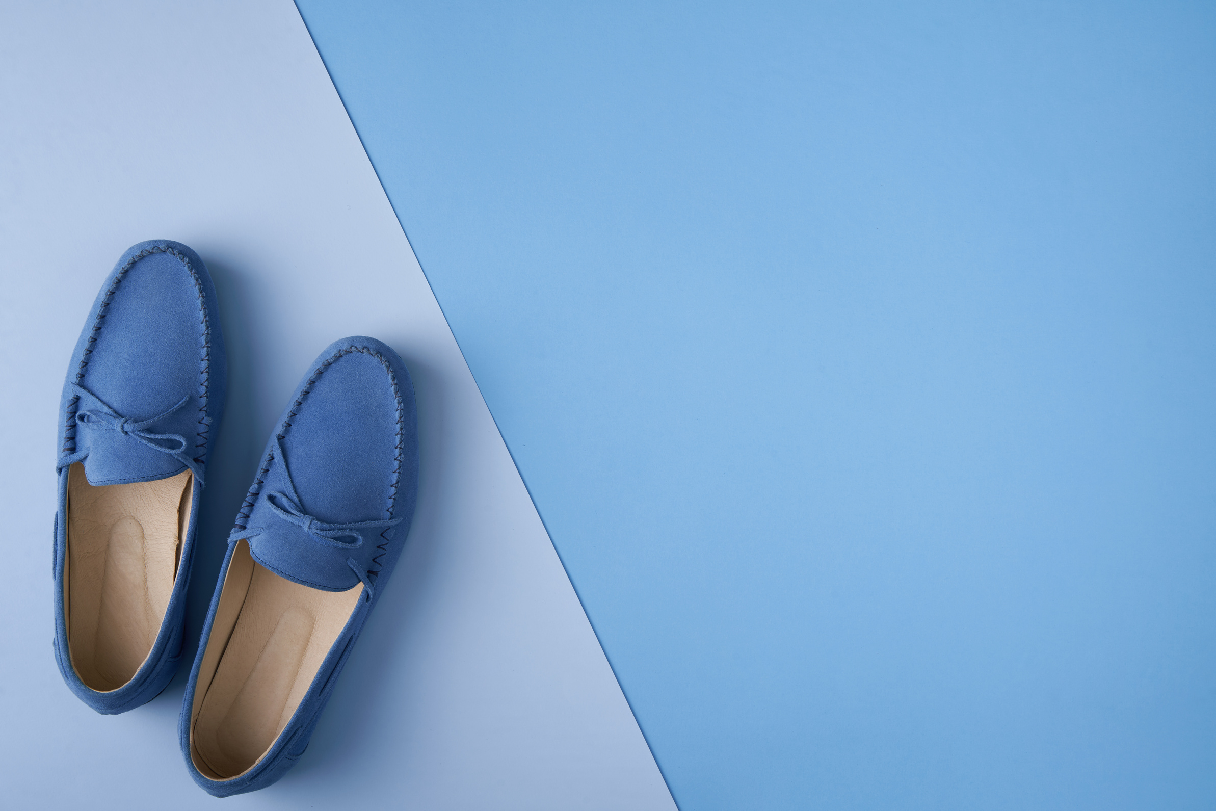 Blue suede man's moccasin shoes over blue background
